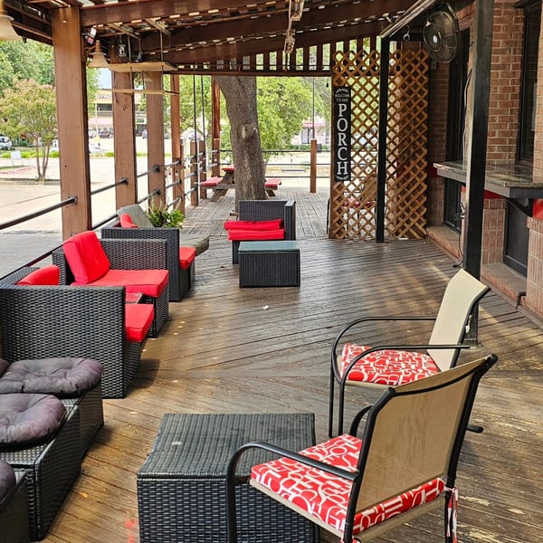 The Back 9 Addison's outdoor patio with wicker seating, red cushions, and a wooden deck.