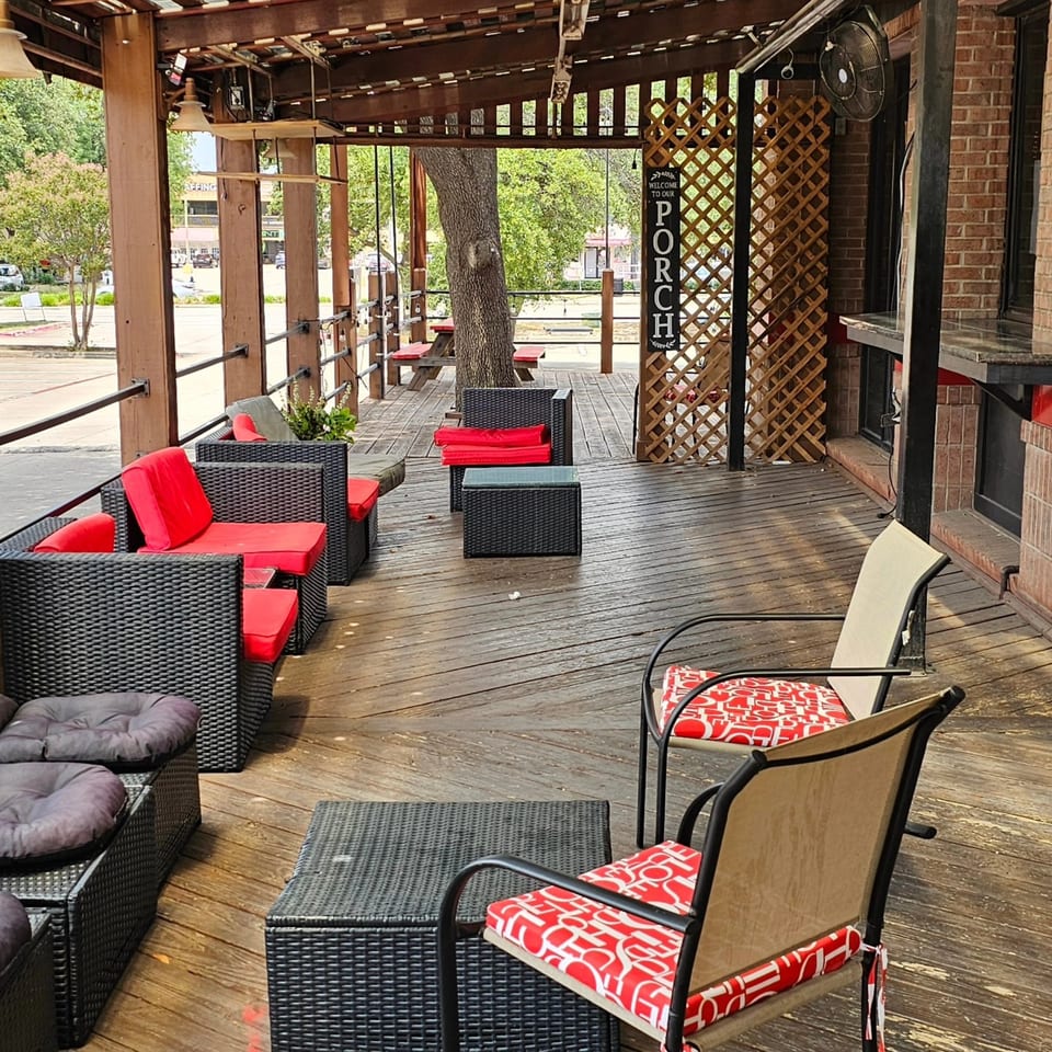 The Back 9 Addison's outdoor patio with wicker seating, red cushions, and a wooden deck.